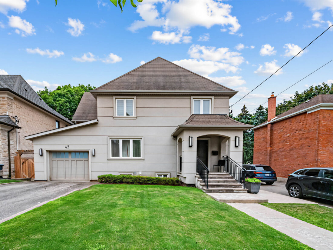 45 Fairholme Ave - front of the two-storey stucco home, with an attached garage and a lawn running to the sidewalk.