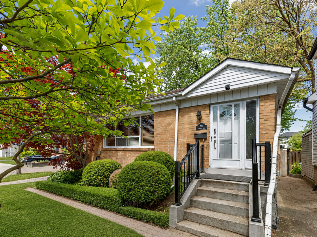 23 Yeomans Rd - brick bungalow with a white gabled entry, clipped shrubs and steps up to the front door.